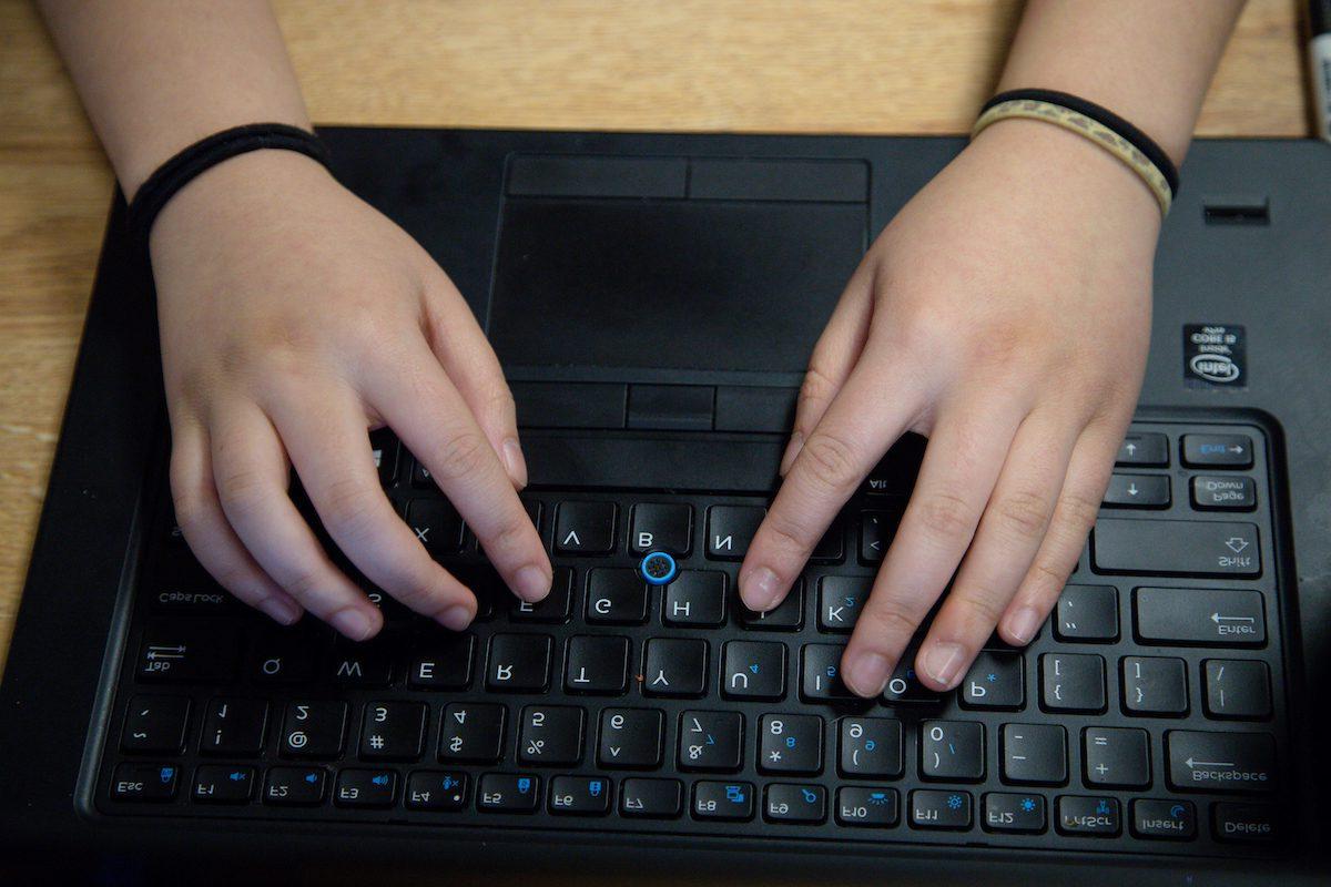 Student's hands seen from above typing on a keyboard